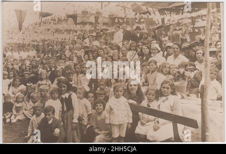 Festa di strada per l'incoronazione di George V, 1911: Gruppo di bambini (e alcuni adulti) all'esterno con conigli appesi di fronte alla strada. La fotografia è stata scattata nella zona di Warwickshire / Oxfordshire, possibilmente Stratford su Avon o Chipping Norton Foto Stock