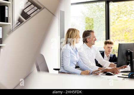 Uomo d'affari che usa il computer con i colleghi in ufficio Foto Stock