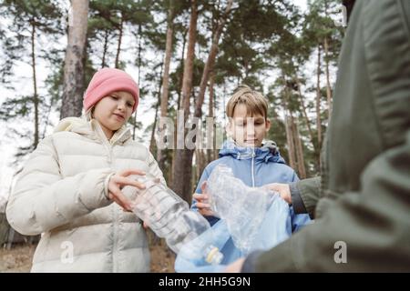 Padre con i bambini che raccolgono rifiuti di plastica nella foresta Foto Stock