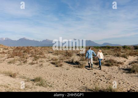 Coppia camminando insieme fra le piante sulla sabbia alle dune Foto Stock