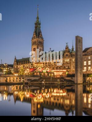 Germania, Amburgo, mercatino di Natale di fronte al Municipio di Amburgo che si riflette nel lago Alster interno al crepuscolo Foto Stock