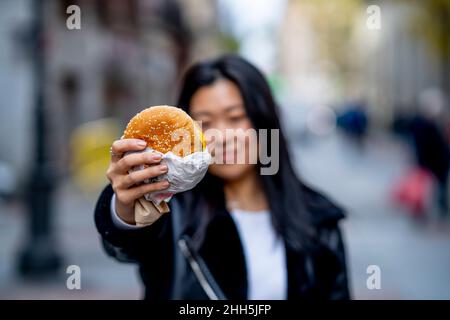 Giovane donna con hamburger in mano Foto Stock
