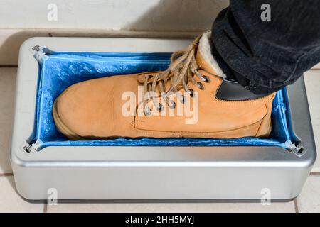 Copriscarpe e un clinthoper, un organizzatore per copriscarpe monouso in ospedale, un uomo mette su scarpe copriscarpe per la pulizia nella stanza, un Foto Stock