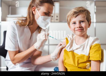 Ragazzo sorridente che viene vaccinato dall'infermiera al centro Foto Stock