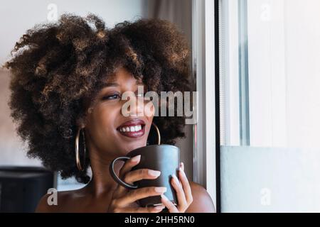 Donna sorridente di bere il caffè a casa Foto Stock