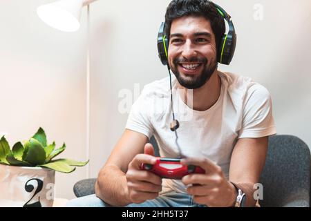 Uomo allegro con cuffie che giocano a casa il videogioco Foto Stock