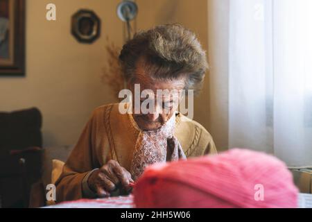 Donna anziana in pensione che si inginocchiava a tavola Foto Stock