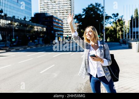 Giovane donna d'affari che si accaparra in città in giornata di sole Foto Stock