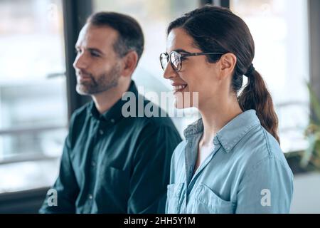 Sorridente architetto seduto da un collega sul posto di lavoro Foto Stock