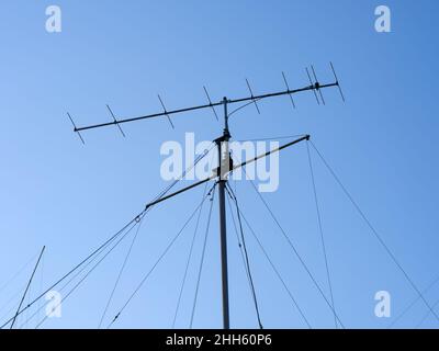 Un'antenna radio VHF con funi di supporto contro un cielo blu Foto Stock