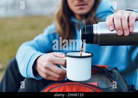 Uomo che versa il caffè dal contenitore per bevande isolato Foto Stock