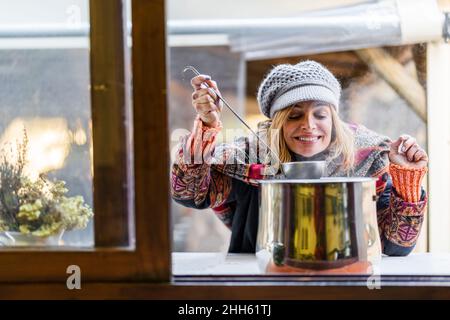 Donna felice con cappello a maglia che prepara il cibo Foto Stock