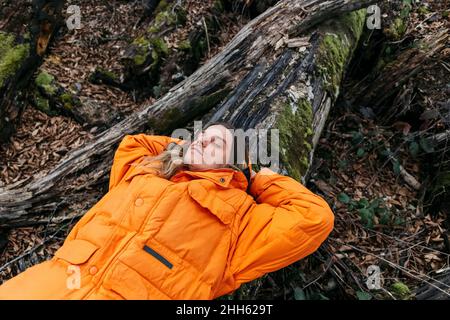 Escursionista rilassante su muschio caduto albero coperto nella foresta Foto Stock