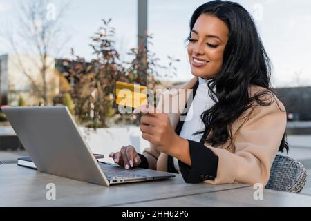 Donna d'affari sorridente con carta di credito che fa shopping online sul laptop Foto Stock