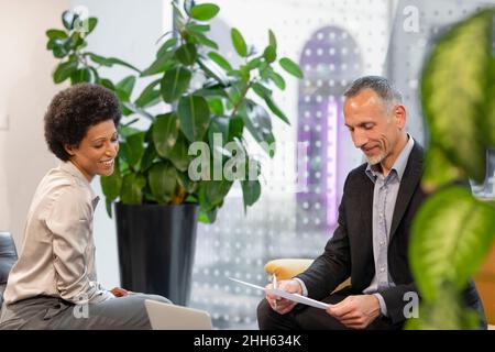 Sorridendo i colleghi che guardano i documenti in ufficio Foto Stock