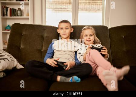 Fratello che gioca il videogioco attraverso il joystick a casa Foto Stock
