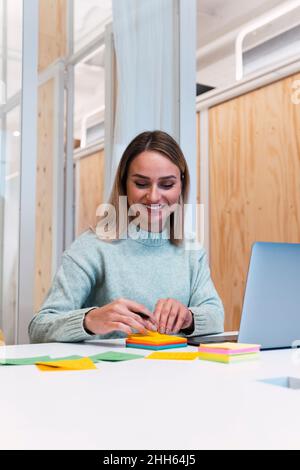 Donna che lavora con appunti appiccicosi sulla scrivania dello studio Foto Stock