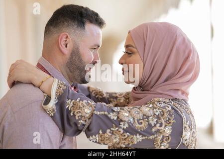 Donna sorridente in hijab guardando l'uomo Foto Stock