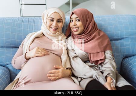 Amici felici seduti sul divano a casa Foto Stock