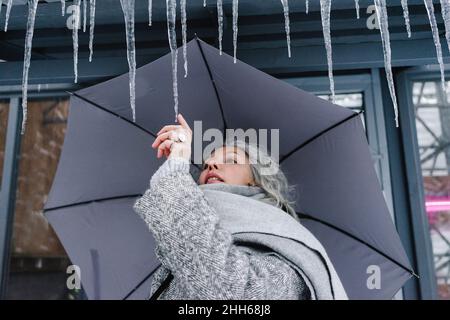 Donna con ombrello che tocca le ghiandole in inverno Foto Stock