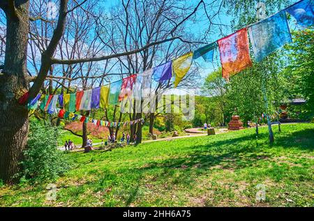 Il prato verde con bandiere di preghiera buddista appese colorate nel Giardino Tibetano del Giardino Botanico di Kyiv, Ucraina Foto Stock