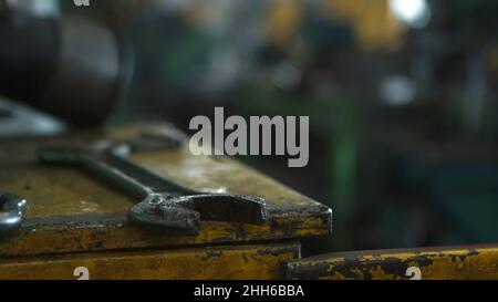 Primo piano della chiave vicino a macchine industriali in una vecchia fabbrica. Officina industriale Foto Stock