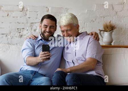 Figlio allegro e padre anziano che prende selfie su smartphone Foto Stock