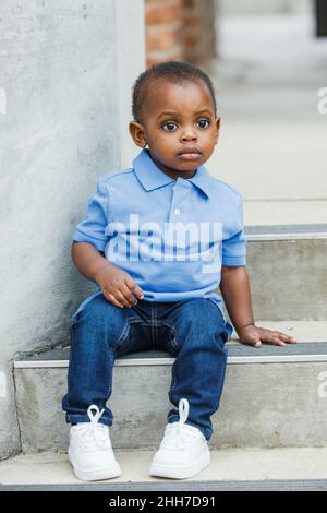 Un bambino carino di un anno quasi prescolare età afroamericana ragazzo con grandi occhi sorridenti e guardando via Foto Stock