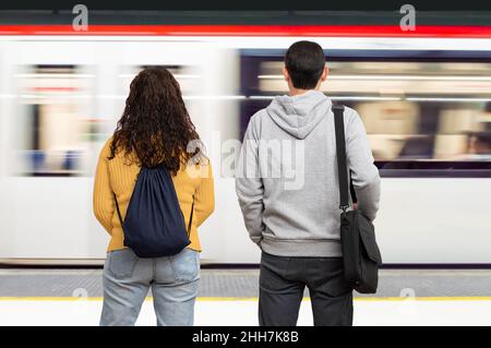 Coppia in attesa del treno nella piattaforma della stazione della metropolitana. Concetto di trasporto pubblico. Foto Stock