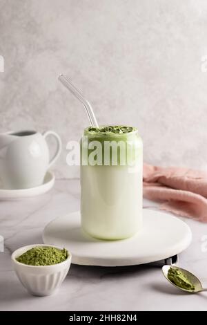 Latte di Dalgona matcha in vetro con polvere di matcha su sfondo bianco, tè verde montato con latte. Foto Stock