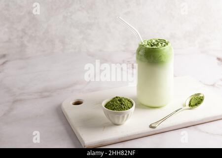 Dalgona matcha latte fatto da panna montata e latte, tè verde in vetro su sfondo bianco. Foto Stock