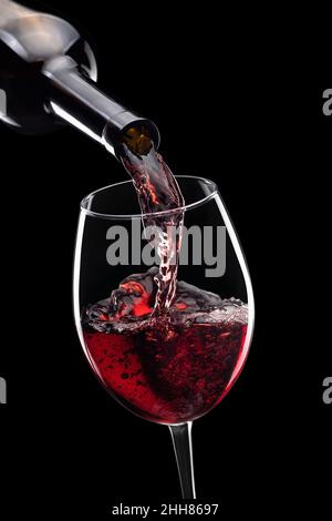 vino rosso versato in bicchiere da bottiglia isolato Foto Stock