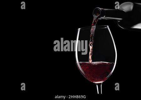 vino rosso versato in bicchiere da bottiglia isolato Foto Stock