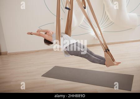 Donna in forma matura che pratica yoga anti-gravità su un'amaca Foto Stock