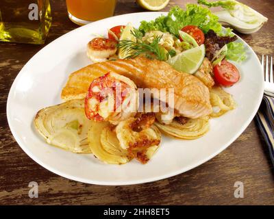 Filetto di pesce fritto in padella a basso contenuto di carb mescolato con verdure grigliate - salmone arrosto e gamberi su un piatto su sfondo di legno Foto Stock