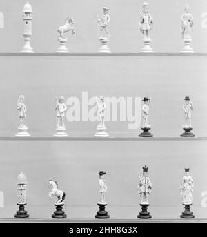 Chessmen (29) ca. 1820 Austriaci i cavalletti, i cappelli e le corone delle figure sul lato (nero) dei tosaerba sono di un corno naturalmente scuro. Su alcuni pezzi del lato scuro sono presenti anche tracce deboli di una macchia arancione-marrone, e tutte le figure hanno tracce di vernice rossa per le labbra. Questo affascinante insieme era originariamente, quindi, molto più colorato di quanto non sia ora. È uno di quegli insiemi in cui il tema dell'opposizione è visto nelle pedine piuttosto che nei pezzi principali, che sono identici sui due lati. Entrambi i re indossano la corona austriaca divisa. I vescovi sono couriers, e la re Foto Stock