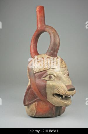 Fox Head bottle 5th–7th Century Moche questa bottiglia in ceramica a forma di testa di volpe vestita con un turbante è stata realizzata da artisti della cultura Moche della costa settentrionale del Perù. Il vaso è verniciato con una striscia rossa e bianca (una sospensione di argilla e/o di altri coloranti in acqua). La volpe indossa un tipico turbante Moche che si estende sulla parte posteriore del collo ed è tenuto da una fascia che va sopra la parte superiore della testa e si lega sotto il mento. Il bordo del turban ha una ripetizione, stilizzato testa di pesce gatto disegno. Il volto della creatura è dipinto con una larga striscia bianca verticale al centro, f Foto Stock