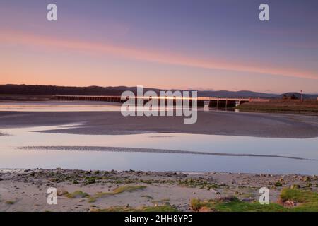 Tramonto al viadotto Kent / viadotto Arnside sopra l'estuario del Kent, Arnside, Cumbria con la marea fuori e un glint dorato Foto Stock