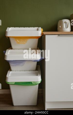 Immagine di sfondo verticale di tre contenitori di smistamento rifiuti impilati in cucina, spazio copia Foto Stock