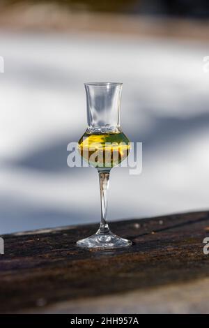 Bokeh foto di un bicchiere di Grappa aromatizzata (schnapps) a Cortina d'Ampezzo, Dolomiti, Italia Foto Stock