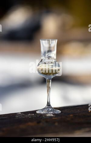 Bokeh foto di un bicchiere di Grappa aromatizzata (schnapps) a Cortina d'Ampezzo, Dolomiti, Italia Foto Stock
