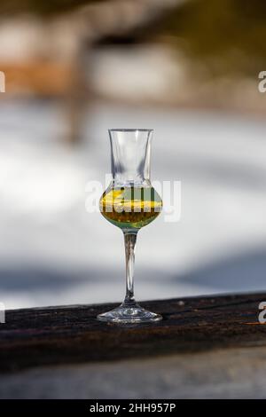 Bokeh foto di un bicchiere di Grappa aromatizzata (schnapps) a Cortina d'Ampezzo, Dolomiti, Italia Foto Stock