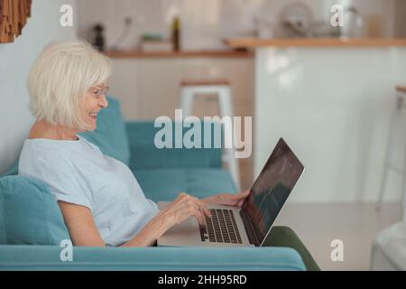 Donna anziana che si rilassa sul divano di casa Foto Stock