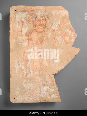 Frammento del pannello con il dio Shiva/Oesho ca. 3rd secolo d.C. Kushan questa rara giuria votiva dell'Asia centrale raffigura una divinità (con nimbus) che viene avvicinata da un adoratore, probabilmente non regale ma raffigurata come di statura uguale al dio. Compositivamente, seguono scene di omaggio e di investitura dall'Occidente post-ellenistico e dall'Iran in cui un re e un dio appaiono fianco a fianco. Insieme alle mani di un adoratore mancante, è raffigurato il dio Siva/Oesho. Quattro armati e tre teste, con un terzo occhio prominente, indossa una pelle animale e una cintura, giubbotto diafanoso e tiene un tridente. Lui Foto Stock