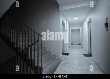Corridoio e scala in un edificio di appartamenti con porte d'ingresso agli appartamenti Foto Stock