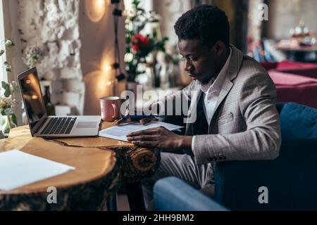 Imprenditore avente il caffè e facendo il suo lavoro in cafe Foto Stock