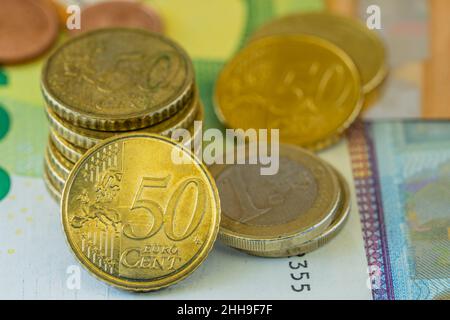 Primo piano delle monete in euro su banconote in euro di valori diversi Foto Stock