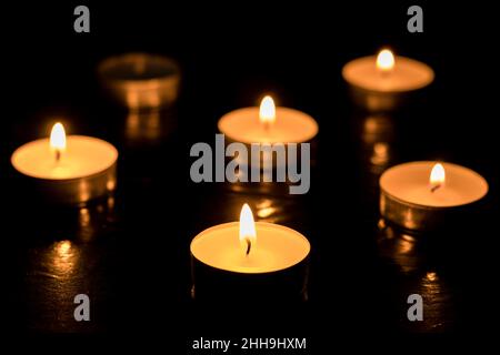 Cinque candele Burning su sei su tavolo scuro, sfondo nero, giorno di memoria. Foto Stock