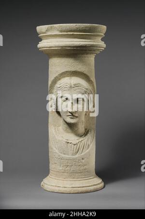 Cippo funerario calcareo (marcatore tomba) 2nd–3rd secolo d.C. romano, cipriota solo un altro cippo funerario di questo tipo è noto, ma le convenzioni utilizzate sono simili a quelle dei ritratti dipinti egiziani. La donna raffigurata qui è chiamata nell'iscrizione greca Kratea. Nel tentativo di catturare la sua individualità, è rappresentata con caratteristiche piuttosto ossee e irregolari, e i suoi capelli sono staccati in mezzo, una convenzione che sembra implicare che era anziana. I suoi gioielli sono intesi come un indicatore della sua ricchezza e stato. Cippo funerario calcareo (marcatore tomba) 241967 Foto Stock
