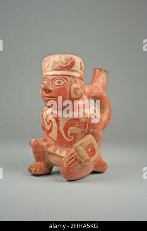 Bottiglia per tubo di lancio a staffa con Guerriero 7th–6th Century Moche (Loma Negra) (?) Questo vaso a lancia, realizzato da un ceramista della cultura Moche sulla costa settentrionale del Perù, raffigura un guerriero che si piega su un ginocchio. La figura indossa un'attenzione che avvolge i capelli e si estende sulla parte posteriore del collo. Il sentore è decorato con vortici in un modello che si abbina alla sua tunica, che indossa su un panno bianco. Indossa ornamenti ad orecchio circolare e tiene un piccolo scudo rettangolare nella mano sinistra e un piccolo mace nella mano destra. Il serbatoio del beccuccio a staffa - la forma del beccuccio richiama t Foto Stock